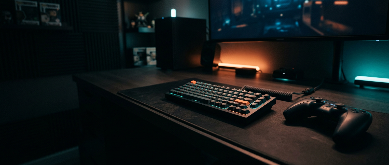 A dark gaming desk with a controller and keyboard